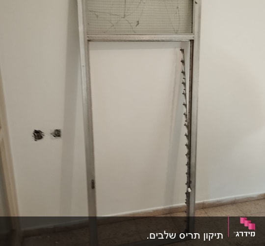 מסגרת תריס מתכת עם רשת שבורה על הקיר